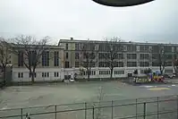 A schoolyard next to a playground (to the right, behind the fence)