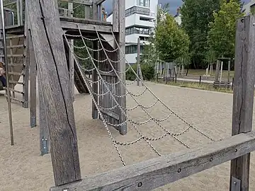 A climbingframe made from material=chain leading up to a platform that is part of a strcuture.