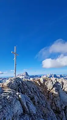 Summit cross on the top of Škrlatica (2740m), with Triglav (2864m) in the back, Slovenia.