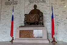 Large bronze statue of a man on a stone pedestal with a flag of Taiwan on either side.