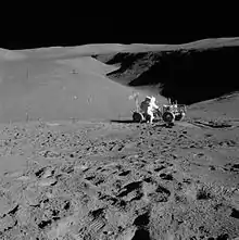 Lunar landscape with man leaning over rover