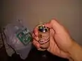 A lighter shaped like a beer can, producing green flame