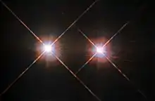 Two white disks side by side, each with coloured fringes and prominent diffraction spikes