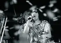 A woman singing into microphones