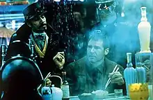 A man with close-cropped hair wearing a brown jacket sits at a counter, holding a pair of chopsticks poised over a rice bowl. Rain cascades down beside him as if from the edge of an awning. In the foreground is a teapot, several bottles, and other dining accessories. Steam or smoke rises from an unseen source. In the background, two standing men look down at the central figure. The goateed man on the left wears a dark snap-brim hat, a black coat with upturned collar, and a gold-trimmed vest. The man on the right, partly obscured by the steam, is wearing a constabulary-style uniform, featuring large wrap-around shades and a hat or helmet with a glossy, stiff brim. There is a bluish cast to the entire image.