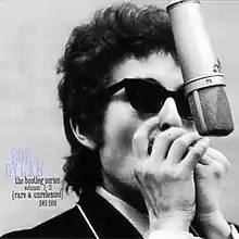 A black-and-white photograph of Dylan playing harmonica