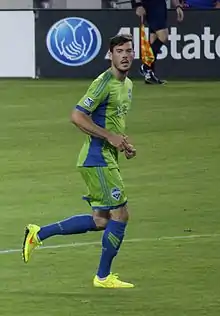 Man in green uniform running on field.