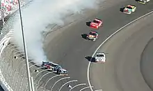 A car spinning sideways with white smoke coming from its rear-end