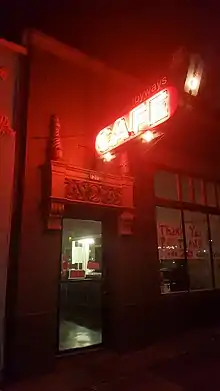 Photograph taken at night of a building's exterior entrance; display next to architectural detail is a neon sign with the text "byways cafe"