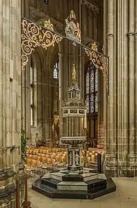 Large yellow stone ornate building with buttresses and square central tower.