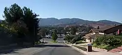View of Kenroy Avenue, looking south towards Soledad Canyon Road, with the San Gabriel Mountains in the background.