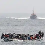Boat overloaded with illegal immigrants, alongside a Spanish coast guard.