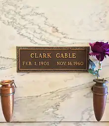 Marble crypt with brass plaque inscribed: Clark Gable, Feb. 1. 1901 Nov. 16. 1960. Two vases are attached to the crypt, one contains a purple rose.