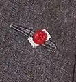 Rosette flanked both sides in silver, denoting the wearer has been awarded the Commander of the Legion of Honour.