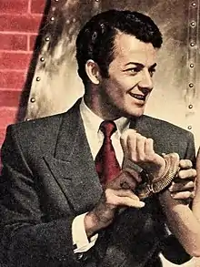 A man wearing a suit and tie is smiling while looking towards the right.