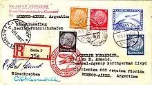 The reverse of a postcard. The consignee's address is in Buenos Aires, Argentina. It bears (on the right, above the address) 25&nbsp;ℛℳ worth of postage stamps and a special Deutsche Luftpost stamp for 2&nbsp;ℛℳ. The stamps are cancelled by a postmark: "Berlin, 26.5.34", and a red cachet saying: "Deutsche Luftpost: Europa-Sudamerika" with a motif of a zeppelin and a Dornier Wal. On the left is the receiving postmark: "Buenos Aires, Argentina 31 May 1934"