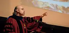 David Carrasco delivers the Harvard Divinity School Convocation Address in front of an image of "Boxcar" by George Yepes.