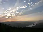 Sunset over a large river flowing through mountains.