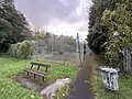 Derelict tennis court that is regularly flooded and is overgrown with reeds and vegetation