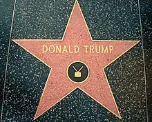 A red star with a bronze outline and "Donald Trump" and a TV icon written on it in bronze, embedded in a black terrazzo sidewalk