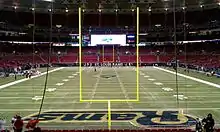  Photograph of a football field taken from the end zone showing goal posts in the foreground