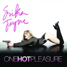 A woman kneels seductively on the ground and points the gun out in front of her.