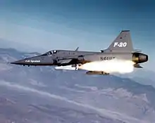 Gray jet fighter aircraft fires a white missile.