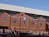 Brick facade of a stadium with a mosaic with a claret background and Aston Villa in gold writing.