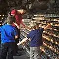 A mother and her children lighting candles at the grotto