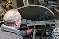 Demonstrating the shear hammer by cutting a segment of red hot cast iron bar which had previously been flattened tilt hammer