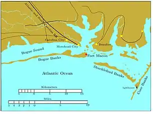 Bogue Banks is a long, narrow island extending from the left edge to past the middle of the chart. Fort Macon is at its eastern end. About two miles to the southeast is the western end of Shackleford Banks, which extends to the east southeast about seven miles. It is separated by a narrow inlet from Core Banks, which extends off the chart to the northeast. Behind these banks are the sounds, ranging in width from one to five miles. Carolina City, Morehead City, and Beaufort are sited on the sounds, all within 10 miles of Fort Macon. The Atlantic and North Carolina Railroad begins in Morehead City and runs off the map to the northwest.