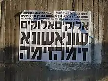 Two identical side-by-side posters on an outdoor wall reading "God hates lechery" in Hebrew