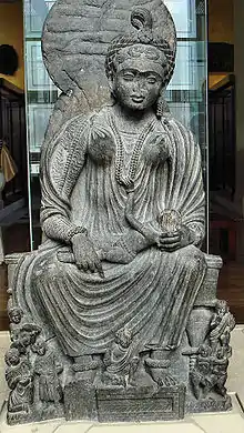 Statue of seated Hārītī with children from Yusufzai in the British Museum, 2nd-3rd centuries CE.