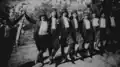 Group of men dancing dabke in Beirut while wearing labbadehs covered with keffiyehs and agals, 1910