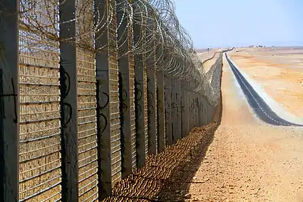 Image 12A more recent section of the Israel-Egypt barrier fence, north of Eilat, June 2012. It is a  border barrier built by Israel along its border with Egypt. It was originally an attempt to curb illegal migrants from African countries. Construction was approved on 12 January 2010 and began on 22 November 2010.