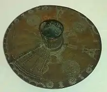 Anklet beaten from a solid brass bar of the type worn by Igbo women. Now in the collection of Wolverhampton Art Gallery. The leg-tube extends approx 7&nbsp;cm each side of the 35&nbsp;cm disc.