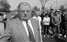 a man in a suit on the street while others look on