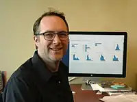"Jeff Heer looking at the camera with a computer screen behind him"