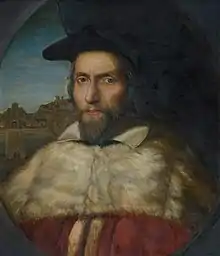 A portrait of a middle-aged white bearded man in academic robes and cap.