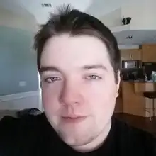 A photo of Joshua Moon at his house with a kitchen in the background