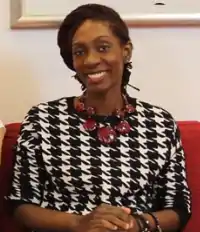 Zollar smiles directly at the camera. She has brown skin and her locs twisted back from either side of her face.