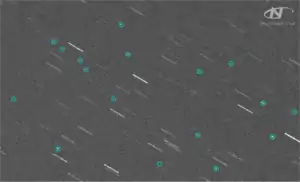 A telescope image showing stars as streaks and Kosmos 1408 debris as circled dots