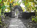 Temple enclosure wall and gate constructed using rubble stone masonry with native teak trees