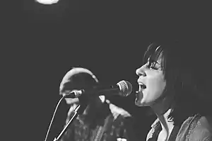 Stevenson singing into a mic, with another performer in the background.