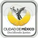 Logo of a black-and-white sculpture, El Ángel. It is a victory symbol personified by an upper naked angel wearing a long skirt. She holds a laurel wreath with her right hand. Below her image, two golden wings are displayed. The slogan "Ciudad de México" is written in black capital letters, with the word "México" bolded, and below the slogan "Decidiendo Juntos" with the same pattern. The whole image is located inside a gray squircle.