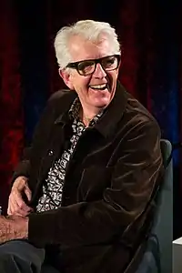 A shot of a white-haired man as he looks away from the camera