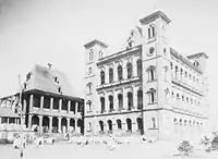 A large multi-storey stone building with peaked roof and decorative arched window arcades