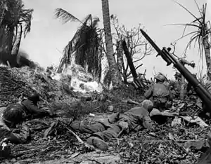 A group of soldiers crawling through a burning jungle, with a hidden bunker in front of them