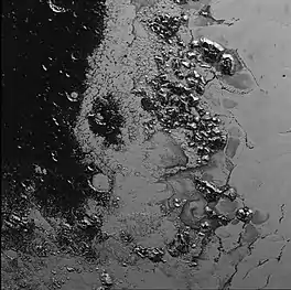 This image shows a region at the border between Cthulhu's "head" (left) and the light, flat Sputnik Planitia (right), with Hillary Montes at center.