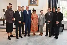 A group of nine people stand in their finery with the tallest on the outsides or a photo inside a room at the Governor Generals house in Wellington.